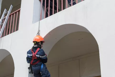 jeune fille de dos en tenue de sapeur-pompier descendant avec une corde
