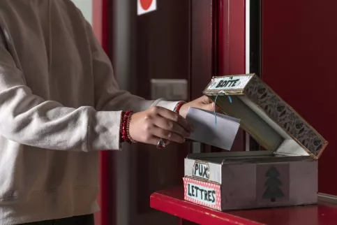 la main d'un évlève qui met une lettre dans la boîte aux letres pour les personnes victimes ou témoins de harcèlement