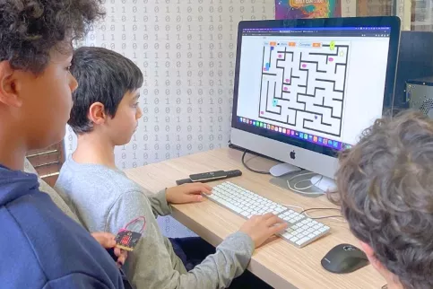 3 élèves regardent un écran d'ordinateur sur un projet de programmation