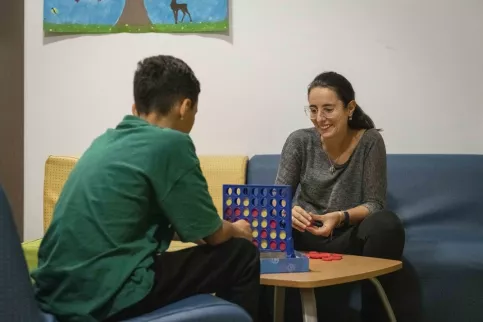 Un jeune en train de jouer au jeu "puissance 4" avec l'animatrice pastorale