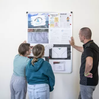 2 jeunes et le responsable sentinelle devant les affiches qui représentent le harcèlement scolaire